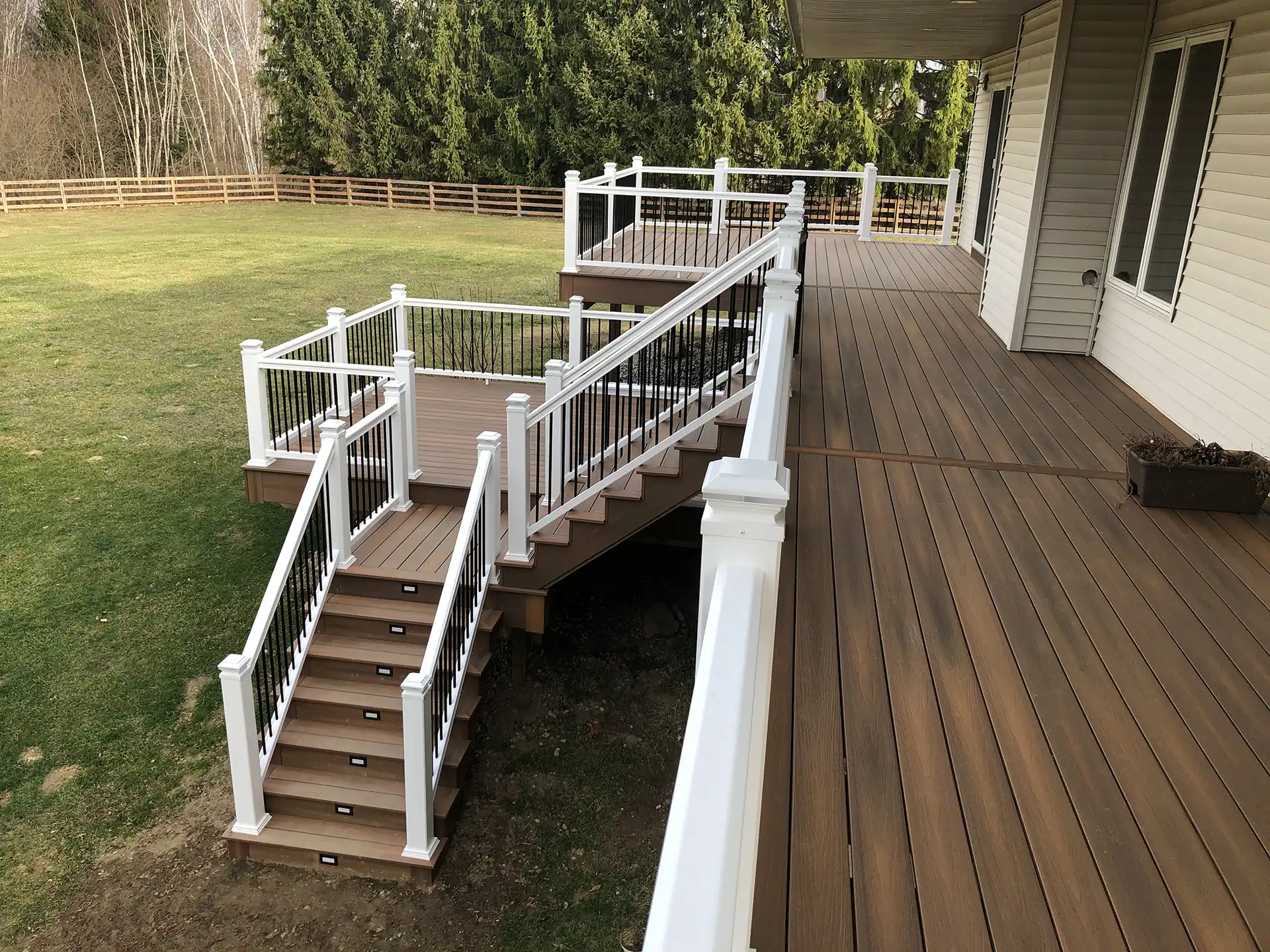 multi-level deck ideas - Photo of an expansive multi-level deck with railing and integrated deck lighting - Multi-level deck designs